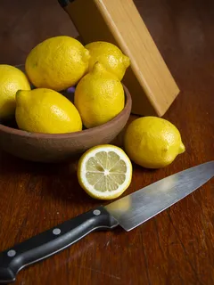 Gesneden citroen naast zwarte mes op houten tafel
