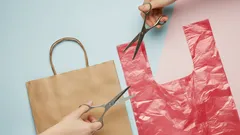 Papieren tas en plastic tas worden geknipt met scharen, milieubewuste keuze benadrukt.