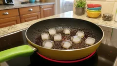 Ijsblokjes smelten in een koekenpan op een fornuis in een moderne keuken.