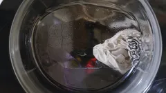 Wasmachine trommel met wassende kleding en water in close-up