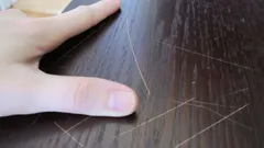 Hand op houten tafel met meerdere krassen in het oppervlak, close-up beeld.