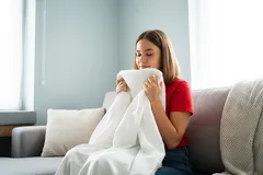 Vrouw op bank ademt in doek voor stressverlichting of angst, thuis ontspannen.